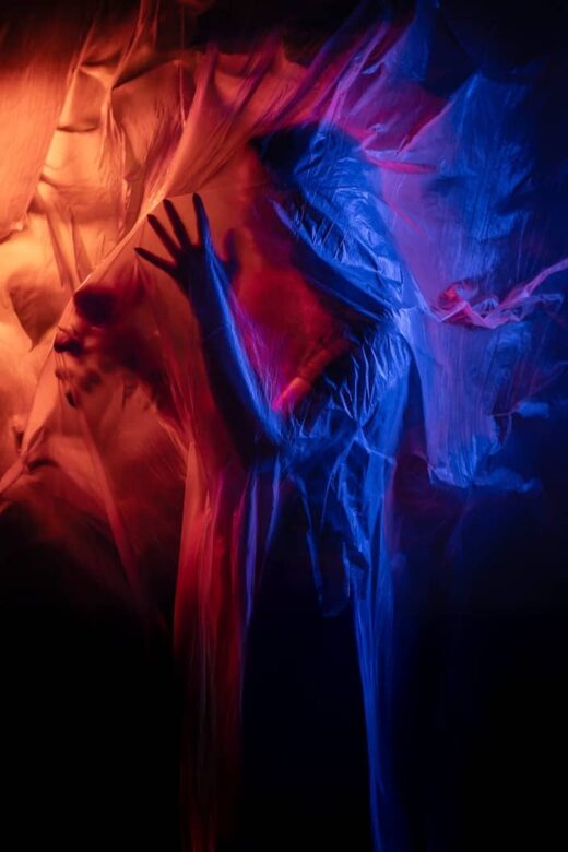 Figure shrouded in translucent fabric with red and blue lights